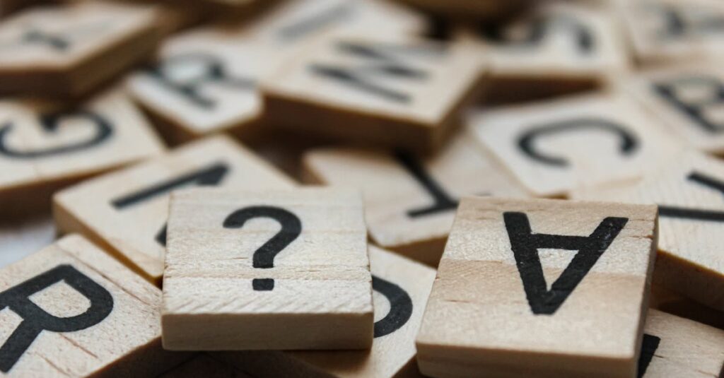 Close-up of wooden Scrabble tiles with letters and symbols, focusing on creativity and language.